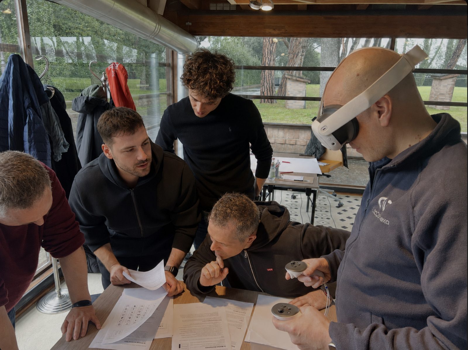 Un gruppo di partecipanti attorno a un tavolo, uno indossa un visore per la realtà virtuale